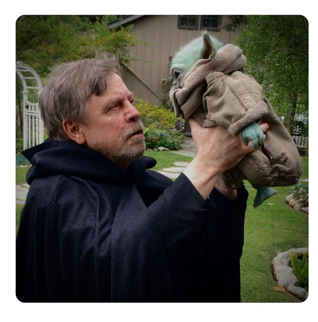 Mark Hamill posing for a picture with Baby Yoda