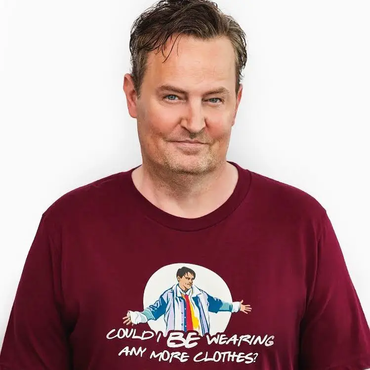 Matthew Perry posing for a photo wearing Friends' merch