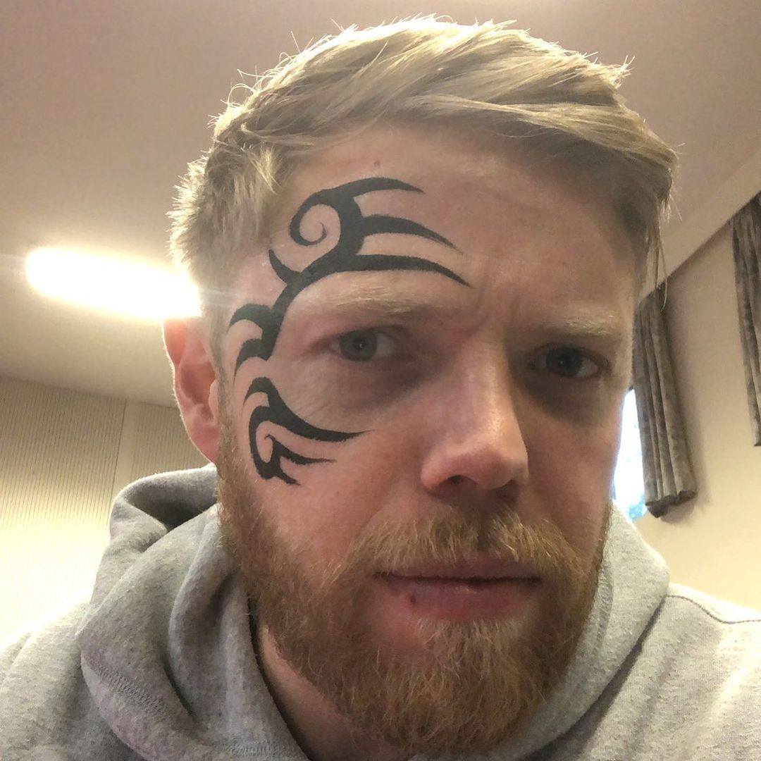 Rob Beckett posing for a picture with fake face tattoos.