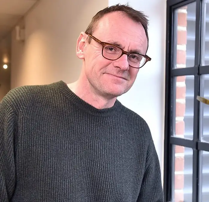 Sean Lock sports his glasses while posing for a picture.