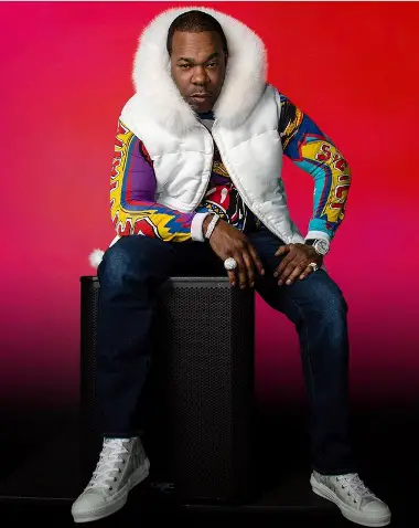 Busta Rhymes sitting down red background